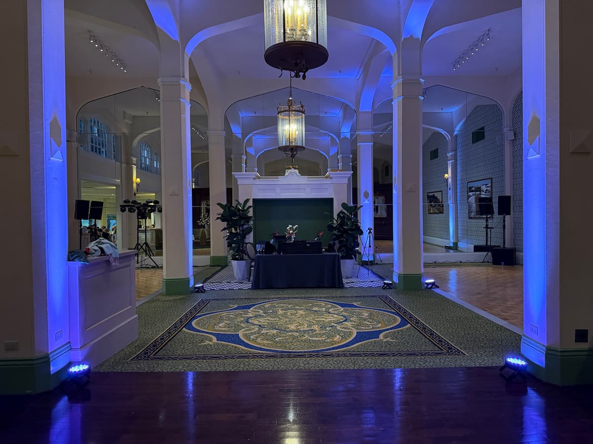 Arched ballroom washed in blue architectural up-lighting with the DJ table at the fireplace