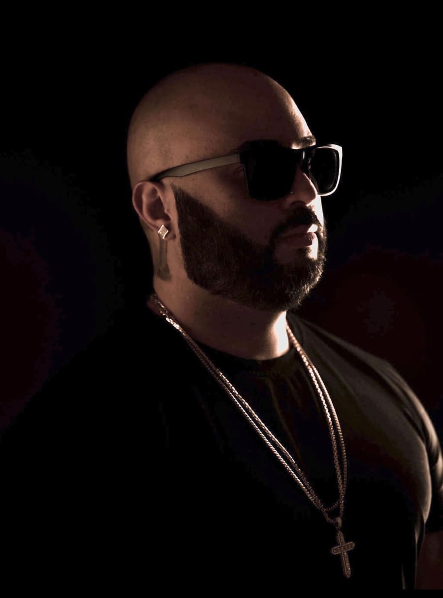 Marcus Gomez, DJ MoeThaMost, in profile wearing sunglasses and gold chains