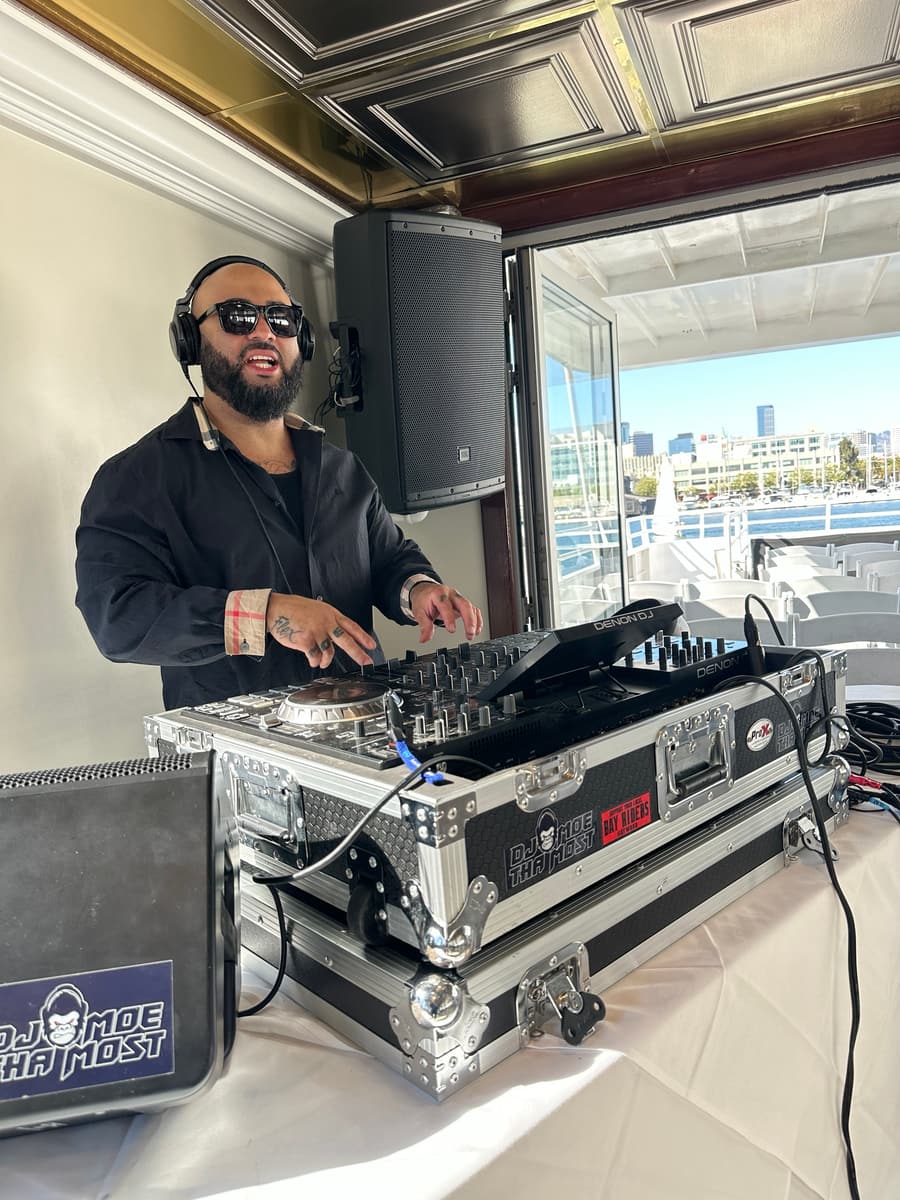 Marcus mixing on a yacht in daylight with the San Francisco Bay skyline behind him and his branded road cases in front